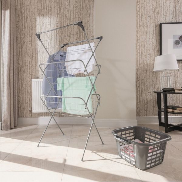 Addis 518018 3 Tier Airer/Hooks - airer/dryer pictured in a home setting with a laundry basket beside it and clothes hanged on the airer