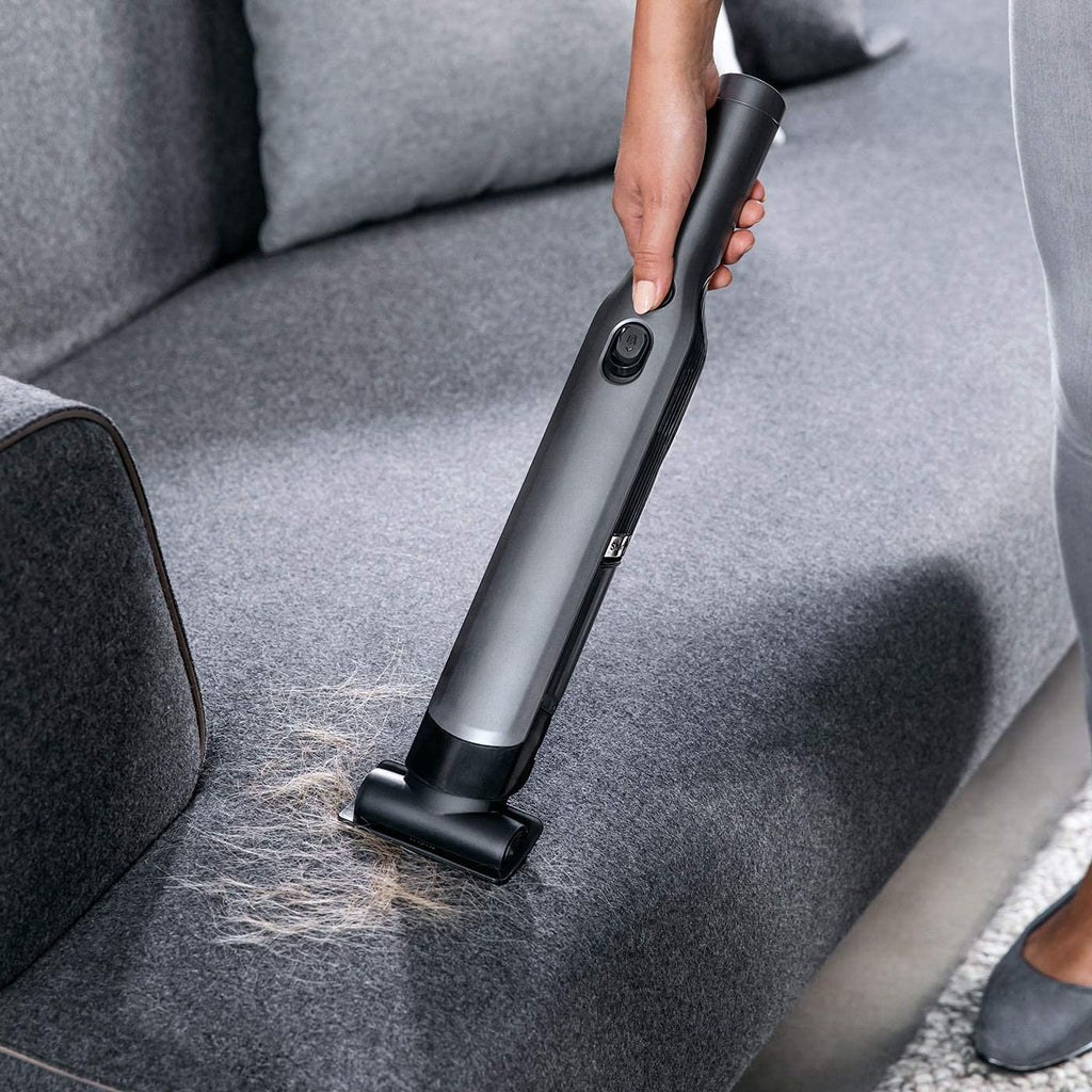 Woman cleaning sofa with Hand Held Vacuum