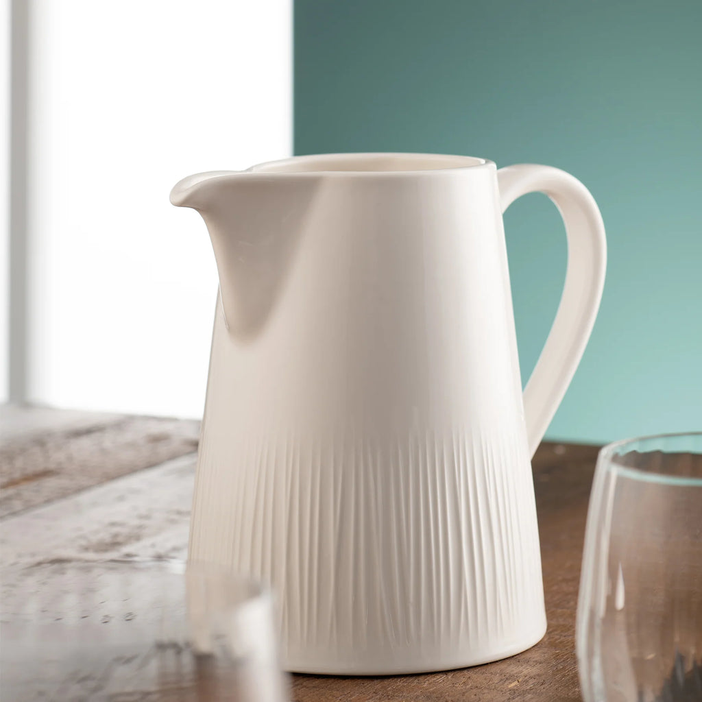Belleek 9314 Erne Pitcher - Erne pitcher jug placed on top of a wooden table beside some glasses