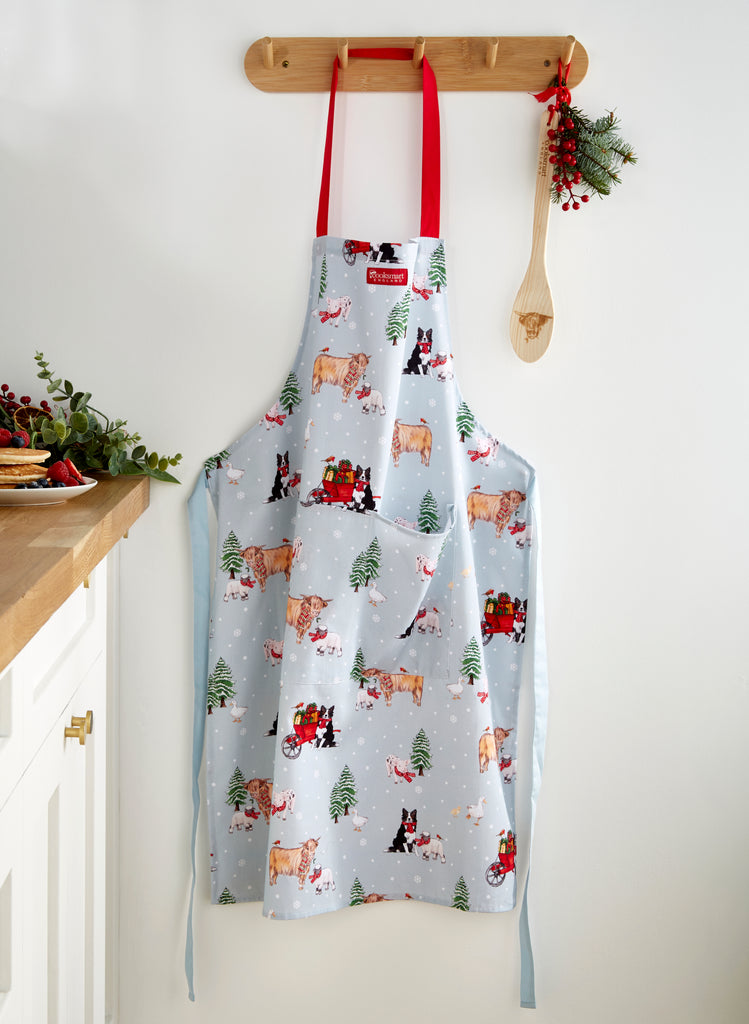 Cooksmart Christmas On The Farm Apron hanging on a wooden hook in the kitchen
