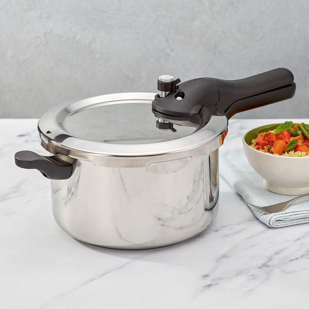 Judge JA75UL 5L S/S Pressure Cooker sitting on a bench with cooked veg behind it.