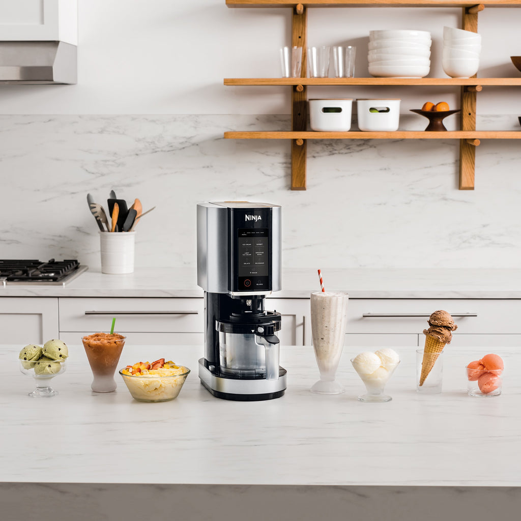 Ninja NC300UK Ice Cream Maker - ice cream machine pictured in a kitchen with different desserts arrayed around it