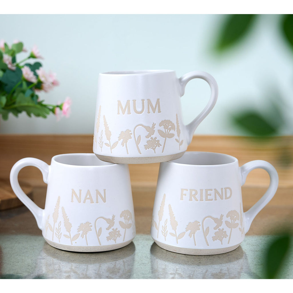 TC168F The Cottage Garden Mug White Floral "Friend" - 3 different designs of the same mug stacked on top of another on a table