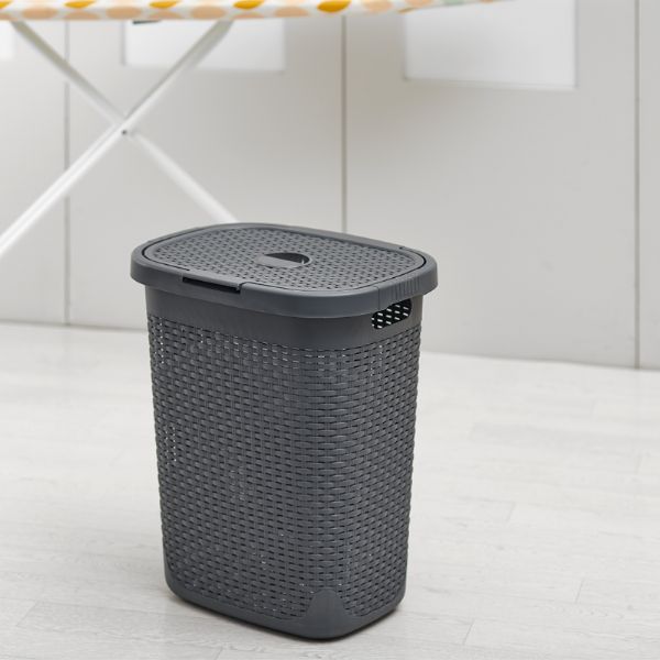 Addis 517485 Laundry Basket 50L Faux Rattan Resin Charcoal showing in beside an ironing board