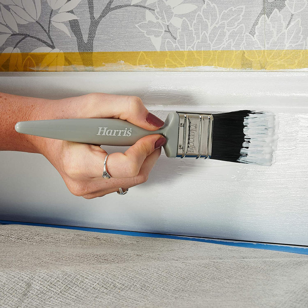 Person using brush to paint skirting board white