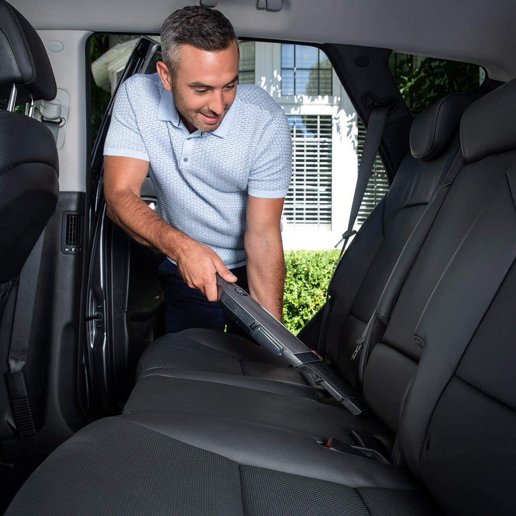 Man cleaning car seats with Hand Held Vacuum